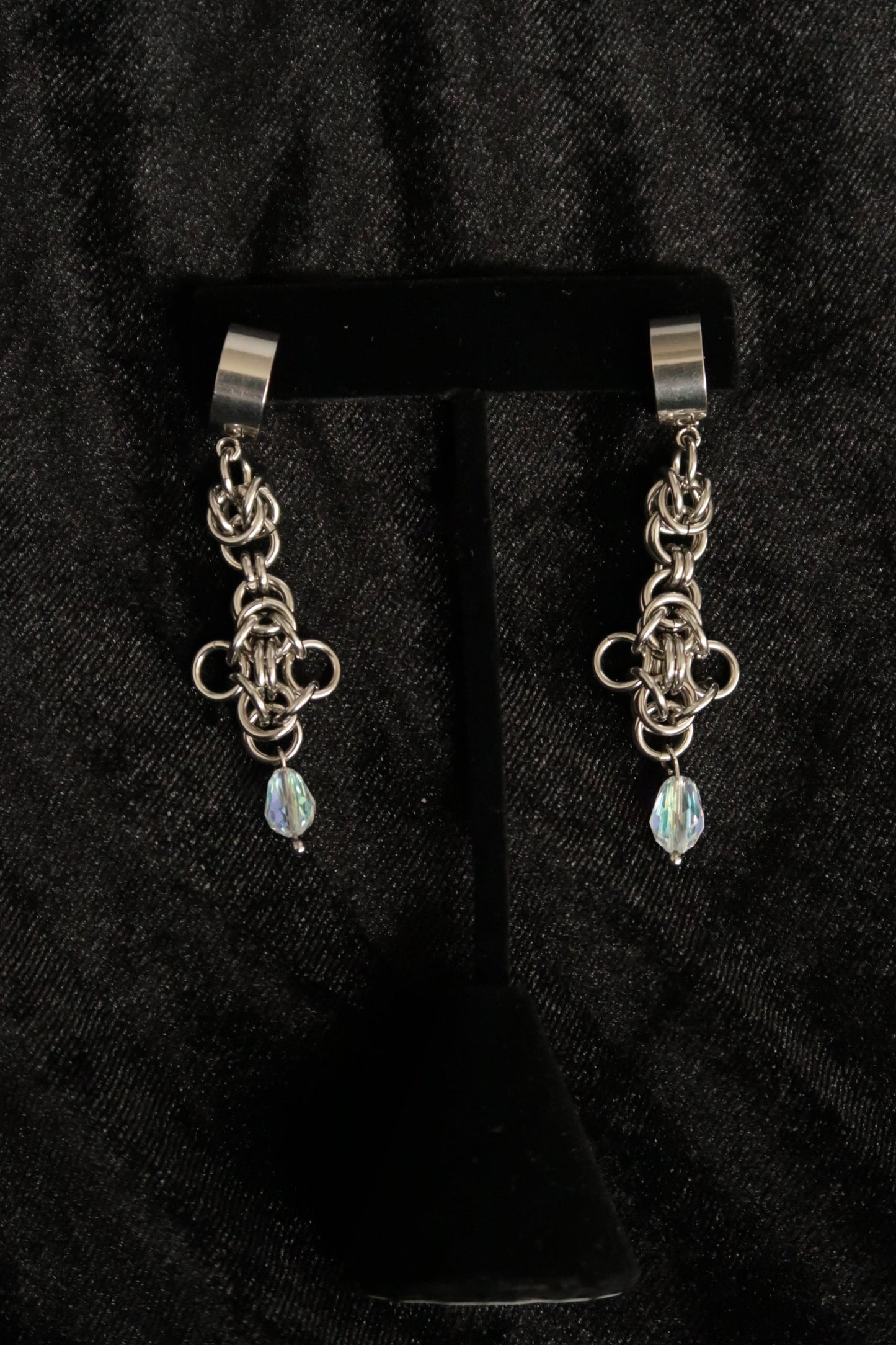 chain earrings with a dangling gemstone on a black background