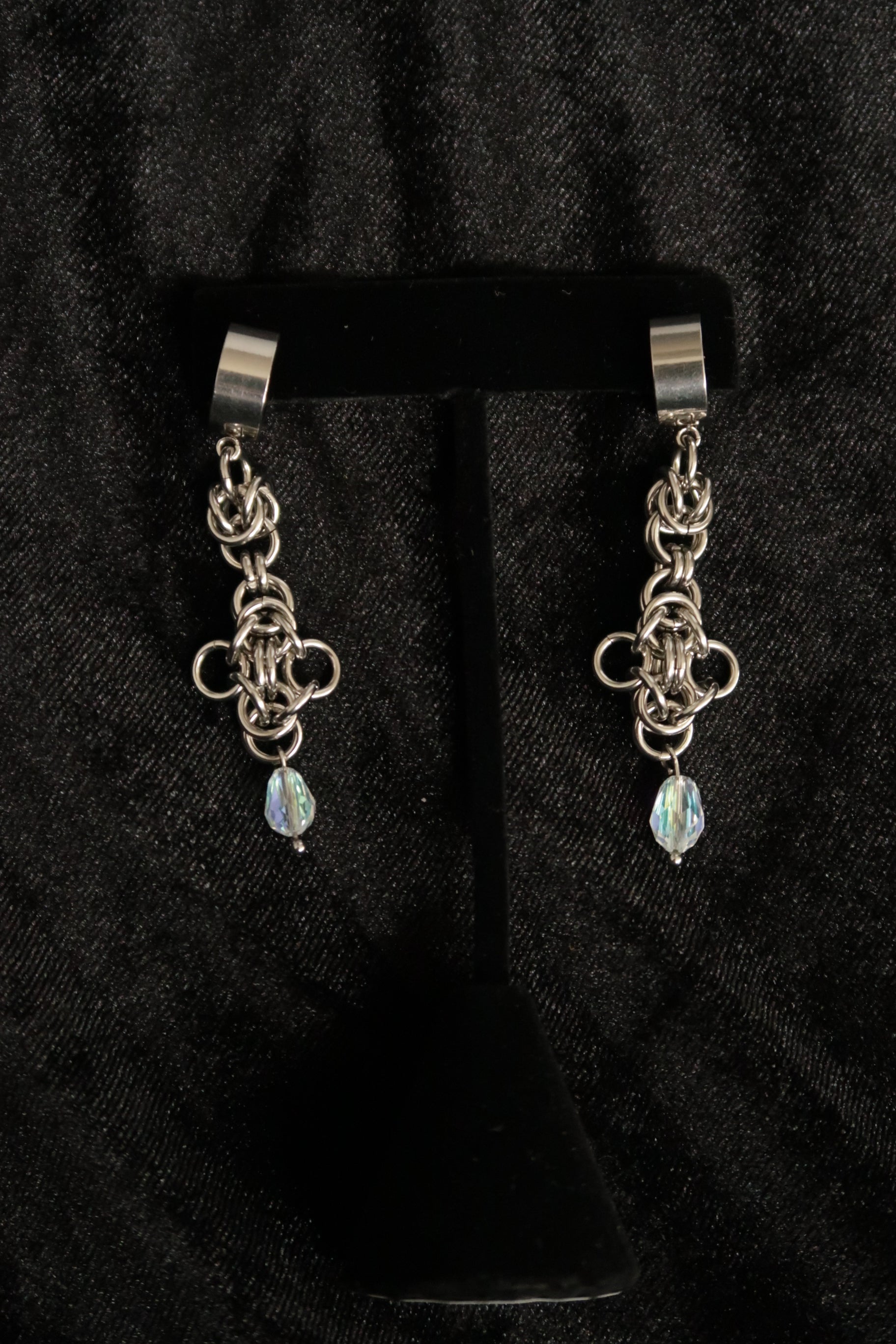 chain earrings with a dangling gemstone on a black background