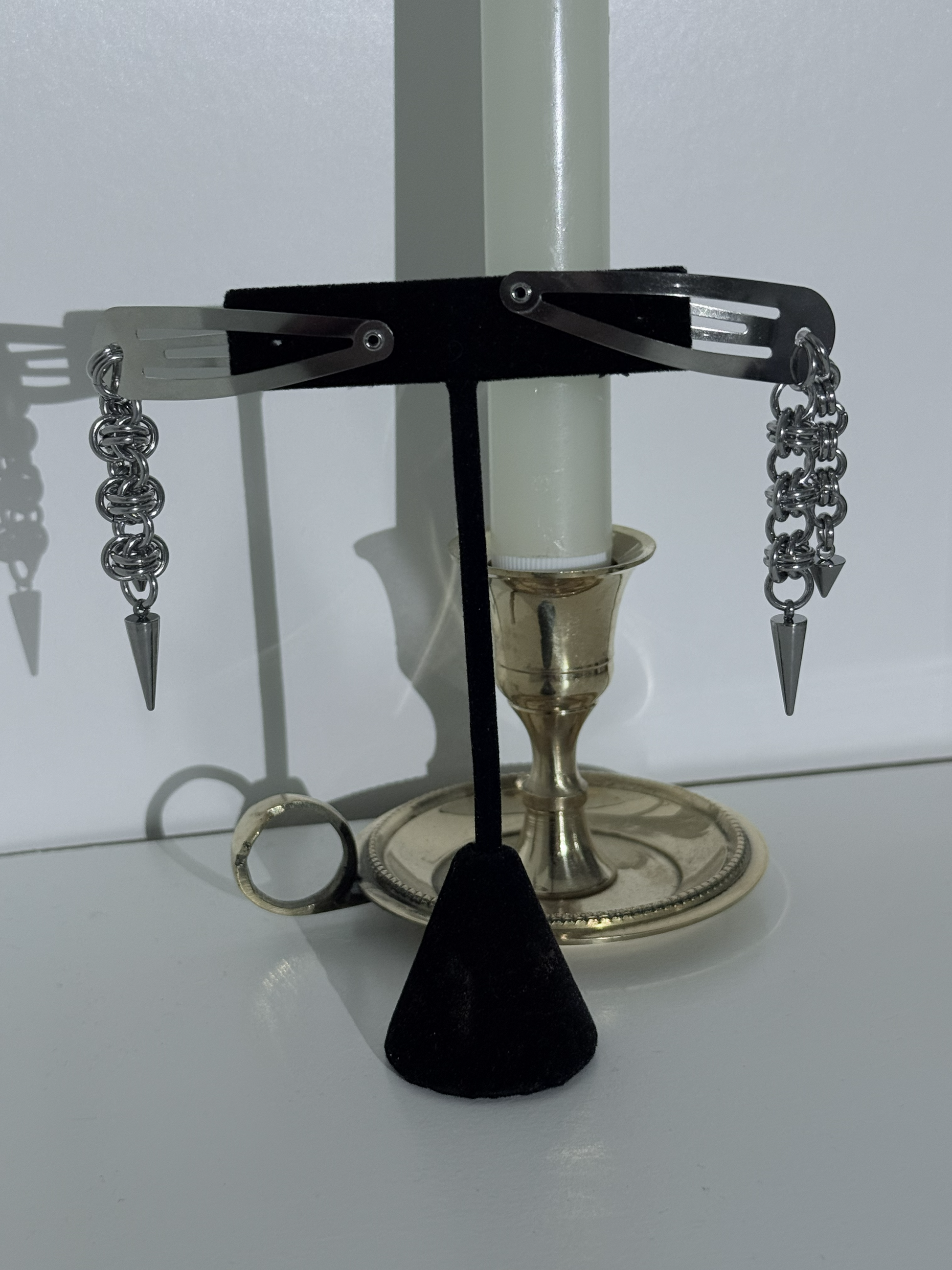 Pair of silver hair clips with black cone on a white surface