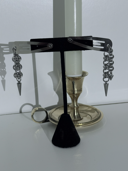 Pair of silver hair clips with black cone on a white surface
